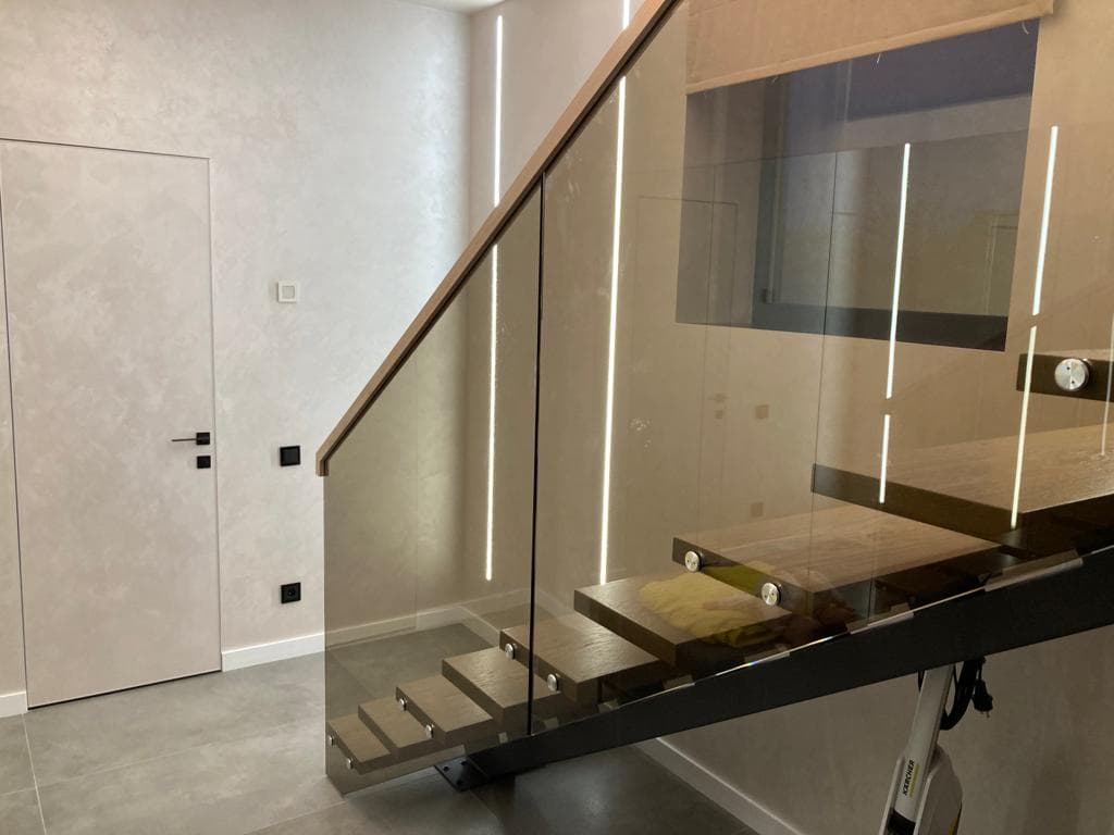 Освещение интерьера отражается на тонированном стекле ограждения лестницы